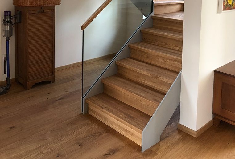 Holztreppe mit Glasgeländer in einem Raum mit Holzboden und Möbeln